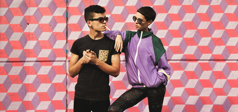 Wild kids/Hip young couple in front of colorful pattern wall in hip/retro /sporty outfit