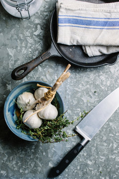 Garlic and thyme in a bowl on a metal table