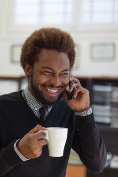 Young african businessman smiling with smart phone and cup of coffee 