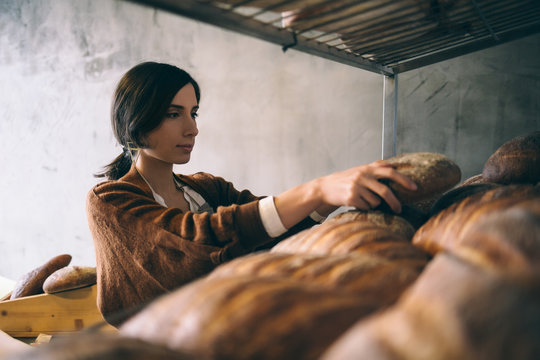 Woman Putting Bread on Shelves at a Bakery