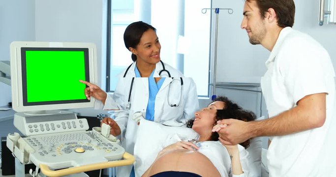 Doctor showing sonography report to pregnant woman on monitor