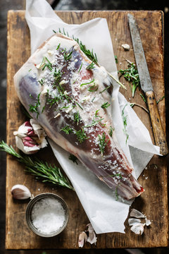 Leg of lamb on wooden board,prepared with garlic,rosemary and mint, ready for the oven 