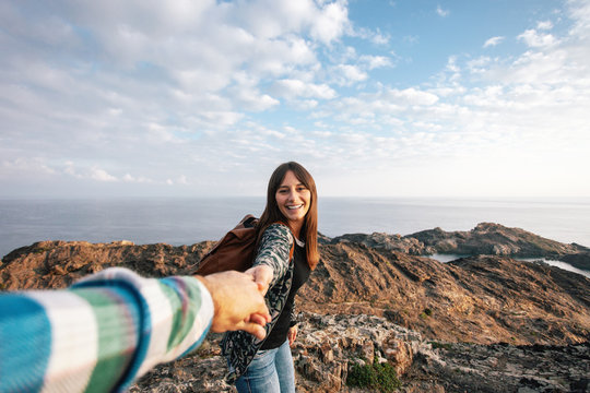 Happy woman holding her boyfriend hand on a beautiful landscape 