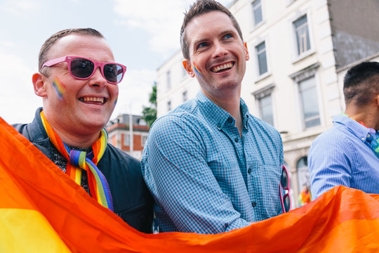 Smiling couple holding rainbow flag during pride parade