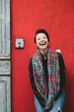 Young woman standing against wall and laughing