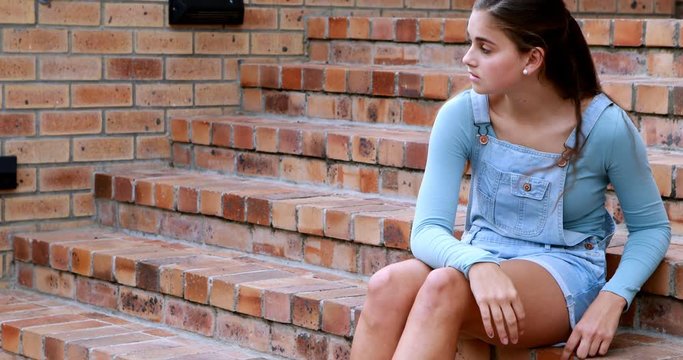 Sad schoolgirl sitting alone on staircase