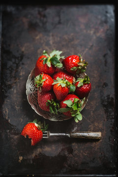 Fresh strawberry's on metal background with fork, one with a bite out of it Seen from above