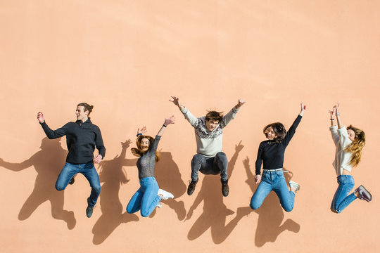 Group of teenage friends jumping in front of a wall