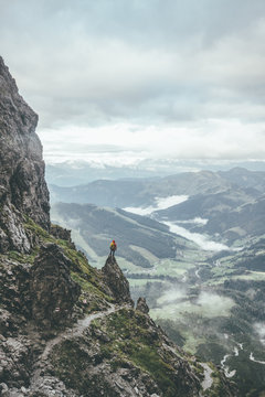 male mountaineer in rugged landscpae standing on a rock overlooking the valley