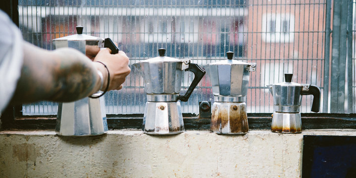 Womans arm reaching for a coffee kettle on a window ledge