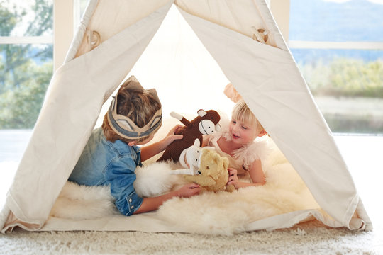 Brother and sister playing in teepee tent in living room