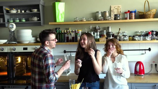 two girls and guy celebrate birthday, drink champagne and eat cupcakes on the kitchen and have a fun