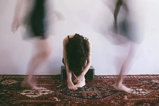 Woman sits with her hair hanging over her face while images of her active self pass by