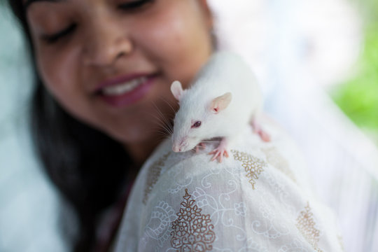 A pet white mouse sitting on the shoulder of a girl