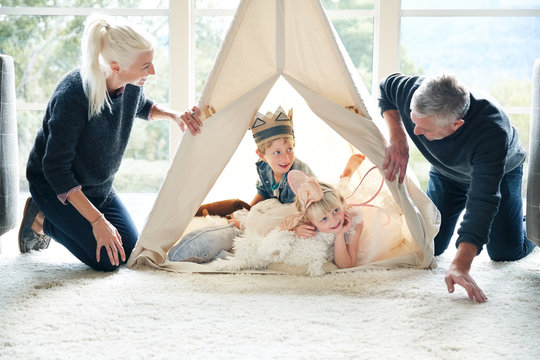 Family playing in teepee tent in living room together 