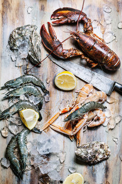 Seafood Lobster, langoustine, oysters and king prawns on ice with lemon on wooden background