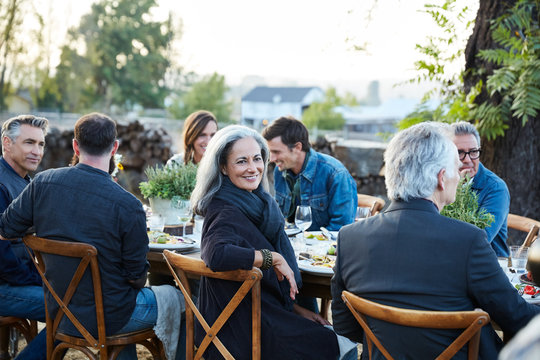 Portrait of senior woman with group of friends enjoying a Farm To Table Dinner Party in backyard