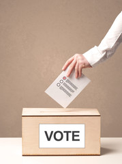 Close up of male hand putting vote into a ballot box