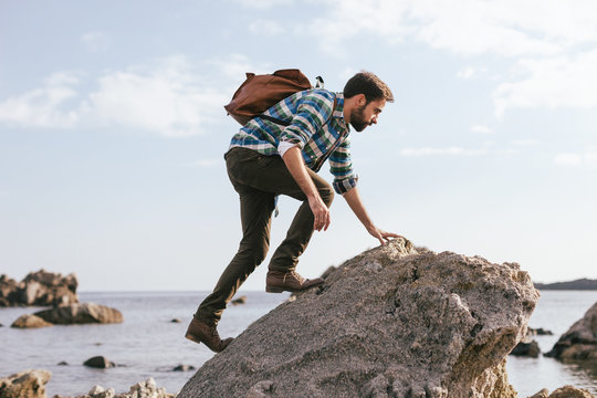 Man on the top of a rock from a beach