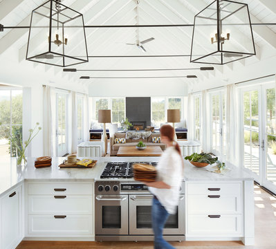 Woman carrying plates in kitchen of modern design farmhouse