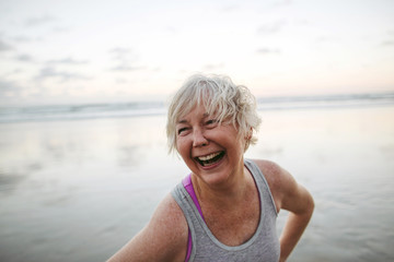 Vibrant mature woman enjoying herself on the beach at sunset