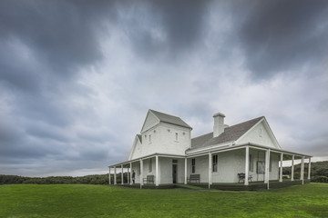 Old farm house in field with cloudy sky