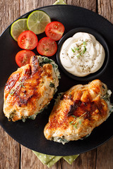 Baked Chicken fillet stuffed with cheese and spinach with sauce close-up. Vertical top view