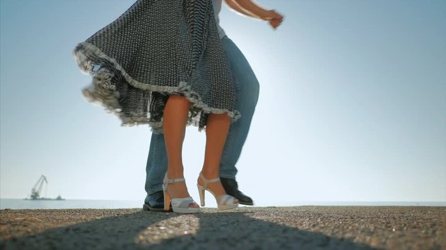Energetic attractive young couple dancing latin Bachata near sea or ocean. Sunlight background. Summer time, romantic footage