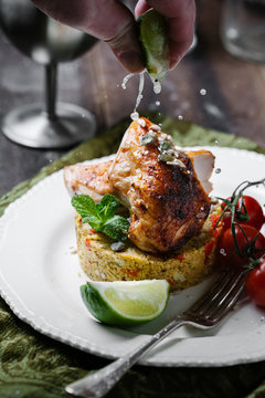 Squeezing a lime wedge over a dish of piri piri chicken and couscous 