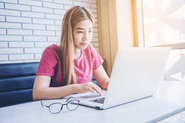 Asian girl working at a coffee shop sitting with mobile phone and laptop. Manager doing job at loft office