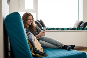 Relaxed teenager at home using smartphone
