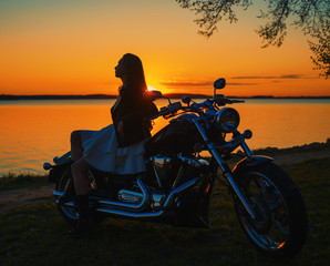 Obraz na płótnie Canvas Young girl sitting on a motorcycle. Sunset.
