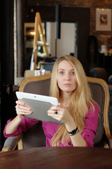 Young girl holding digital tablet and looking directly at camera. Businesswoman in the cafe does business. Office worker on lunch. Women at a meeting in the lobby of the hotel.