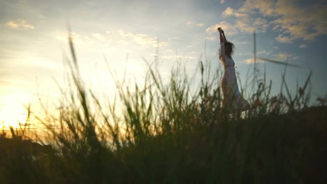 Young beautiful healthy woman white dress dansing cliff raising arms slow motion