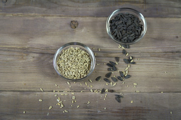 Sunflower in the shell and cleaned sunflower in bowls on wooden background