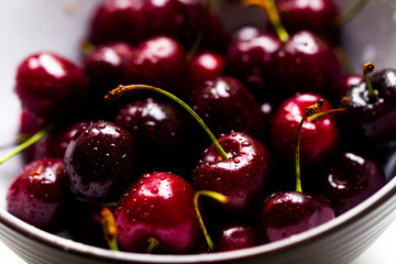 Cherry with water drops in a white-brown bowl on a white background, natural light