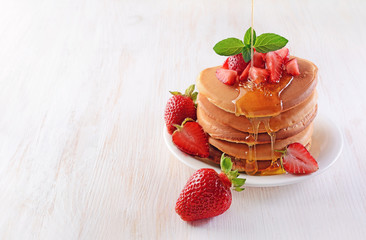 Tasty breakfast. Homemade pancakes with fresh strawberry, honey and mint