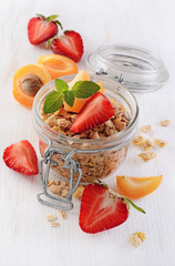 Healthy breakfast. Homemade granola in glass jar with fresh strawberry, apricot and mint