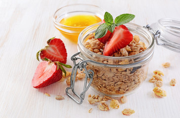 Healthy breakfast. Homemade granola in glass jar with fresh strawberry, mint and honey