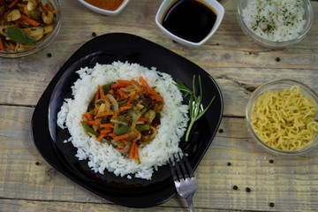 Chinese food on the plate with spices on a wooden background