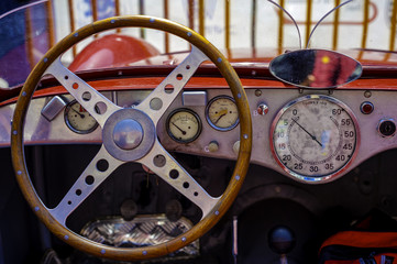 Close-up of the cockpit of vintage retro sports car..Visible the steering wheel, fuel level indicator, oil pressure and water
