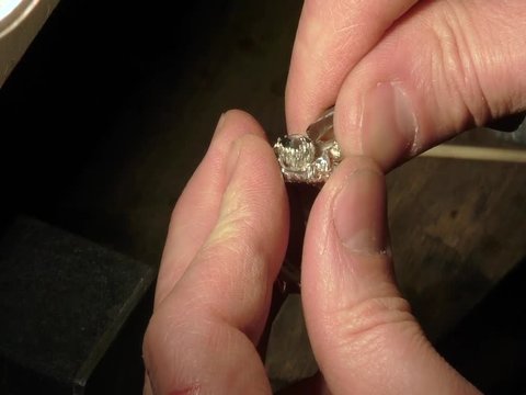 Jeweler is fixing a gem on a ring.