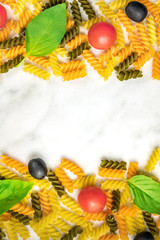 Pasta salad ingredients on white marble with copyspace