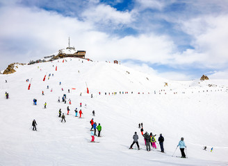 Skiers and snowboarders on the top station slope in Courchevel winter resort, France.