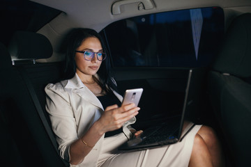 Beautiful business woman sitting in back seat of car