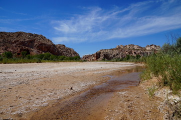 Rising global warming: wide river dried out to a tiny stream riverbed. Rising global temperature increases evaporation and reduces rainfall in arid areas reducing wide streams to tiny runlets.