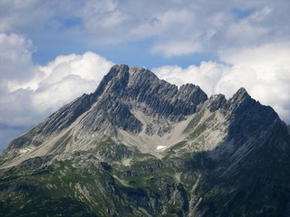 Fototapeta na wymiar Climate change: last remainder of snow instead of an alpine glacier in the bowl shaped depression formed by the mountain glacier in the process of centuries. Lech Valley, Austria, August 2015.