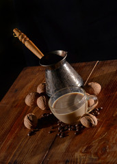 Coffee with milk, Turk and coffee beans on wooden surface.