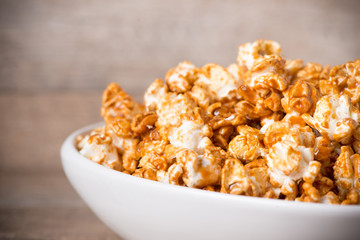 Caramel opcorn in bowl on the wooden table.