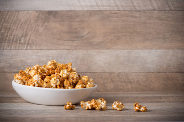 Caramel opcorn in bowl on the wooden table.